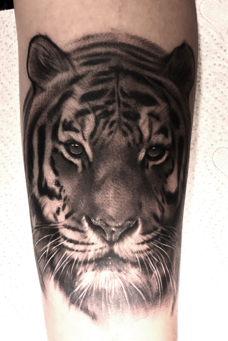 Tattoo-Anansi-Studio-Munchen-Munich-Haidhausen-Alex-Tiger-lower-arm-strong-powerful-nature-jungle-best-black-and-grey-realism-animal-portrait.jpg